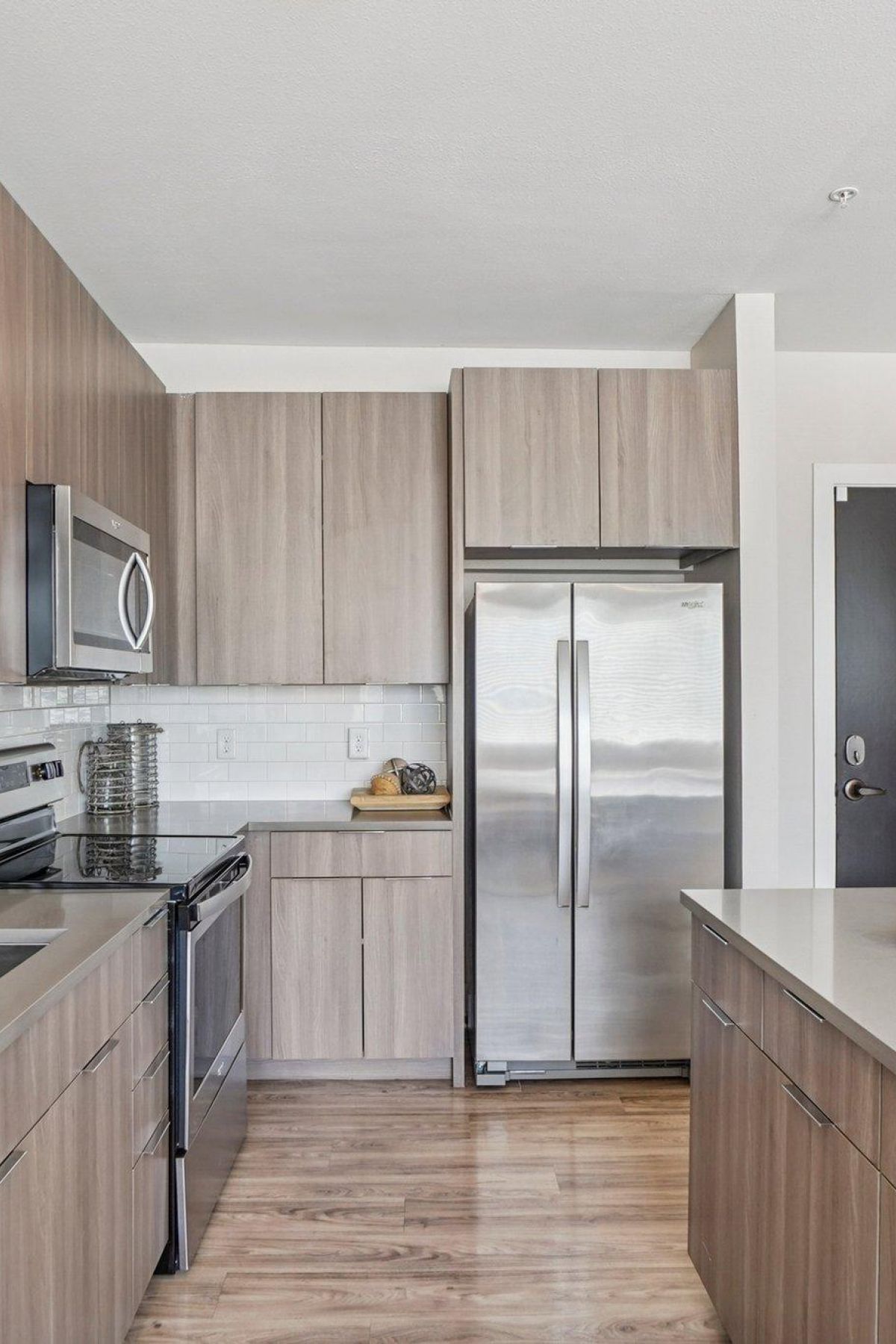 Ascent modern kitchen with wood cabinets, stainless steel appliances, and a central island on a wooden floor.