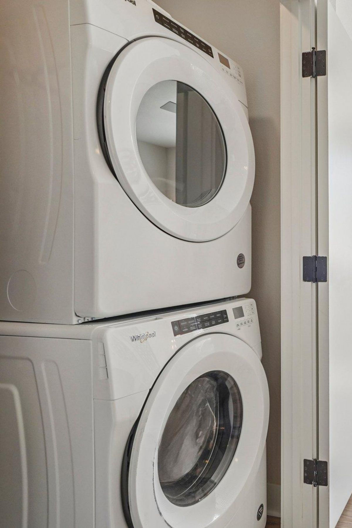 Ascent stacked washer and dryer next to an open door leading to a bright living room with a sofa and coffee table.